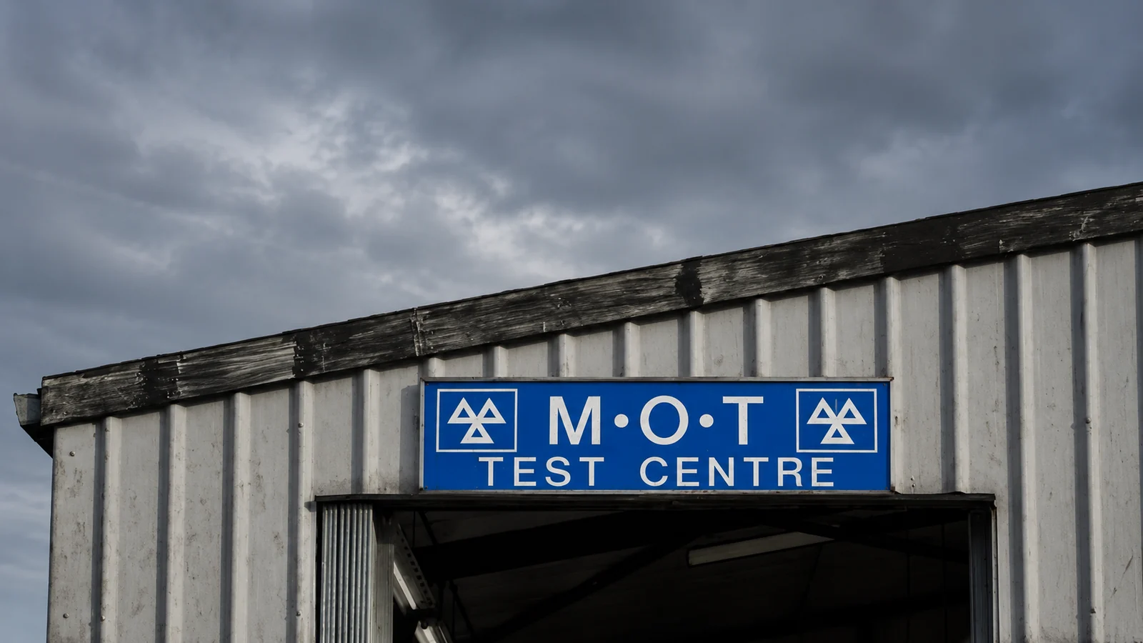 Blue MOT test centre sign above the entrance of a metal-clad garage