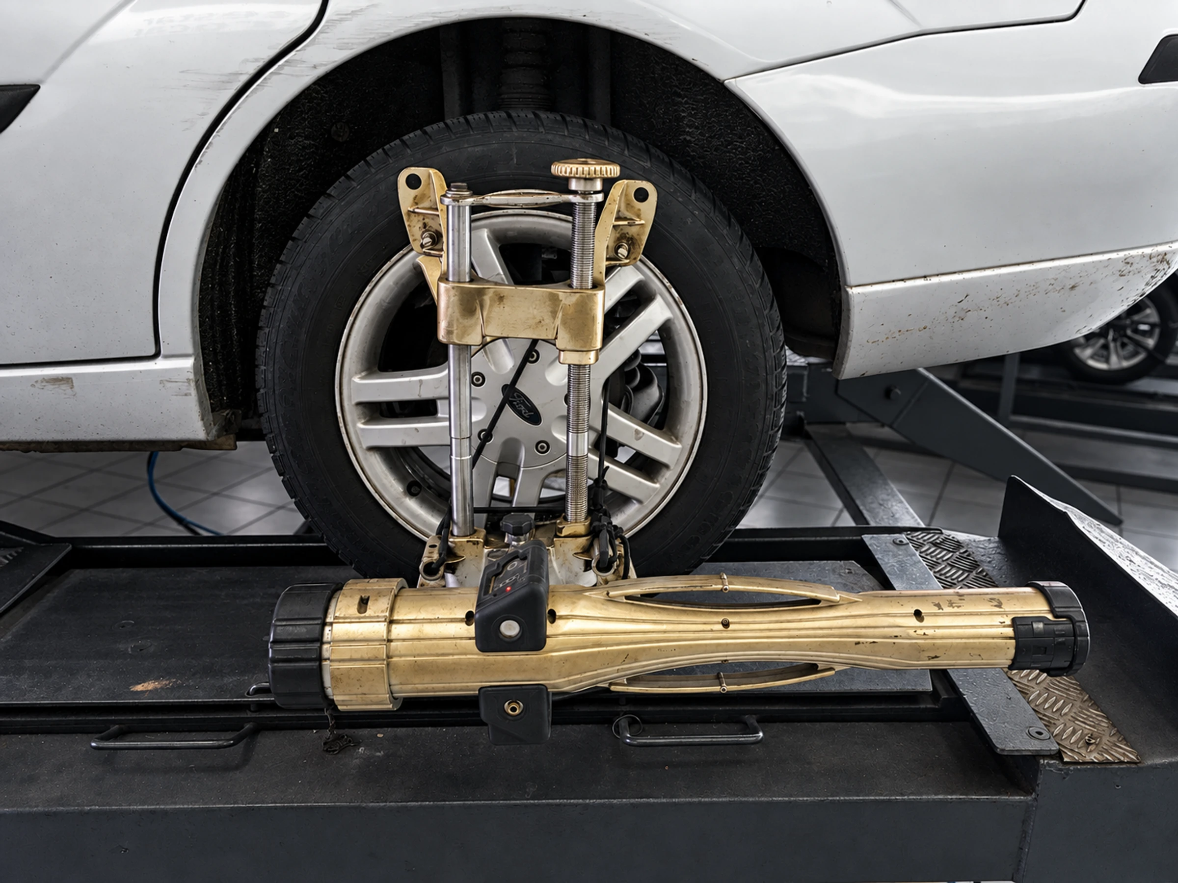 Wheel-alignment measuring head clamped to the front wheel of a Ford Focus on a workshop lift.